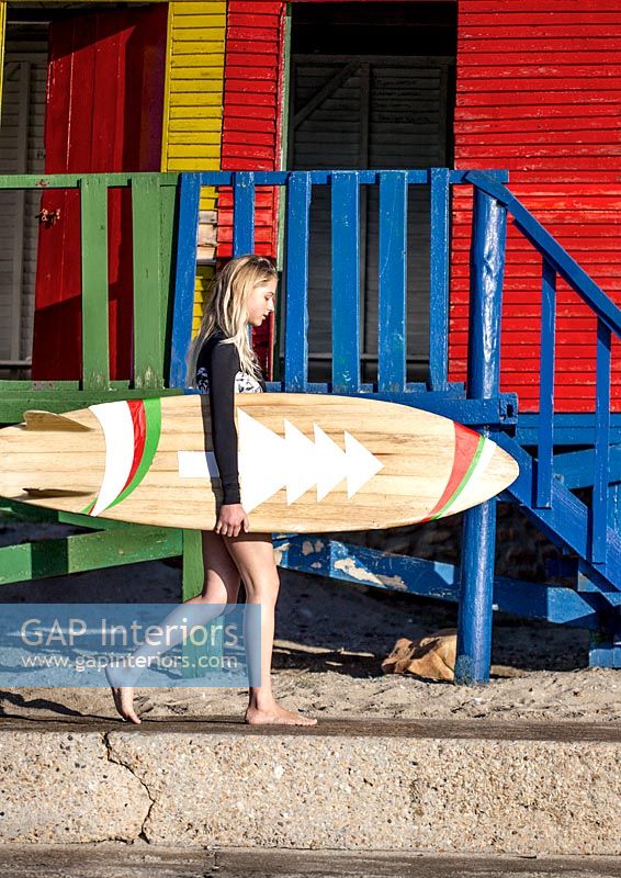 Surfeur à côté de cabines de plage colorées