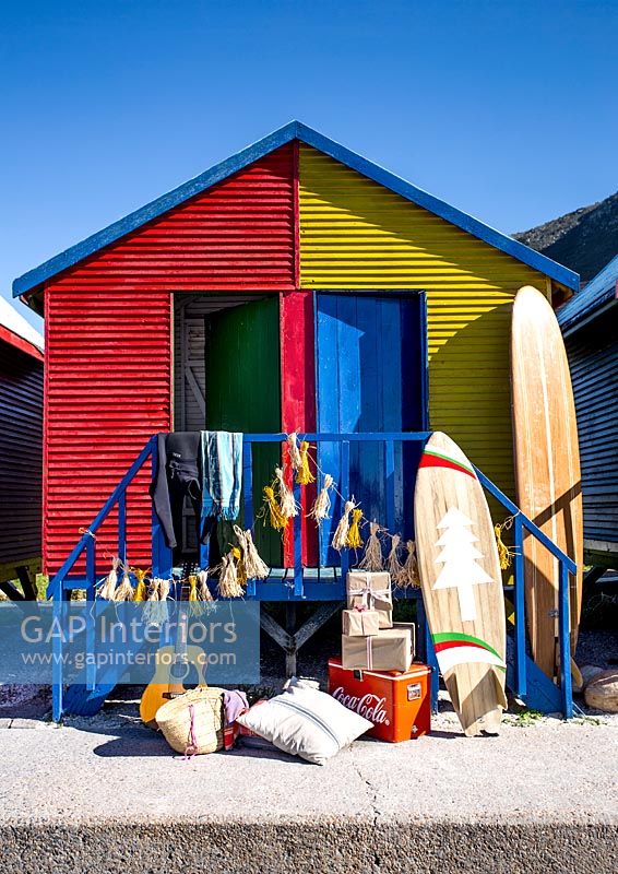 Planche de surf et cadeaux à l'extérieur des cabines de plage colorées