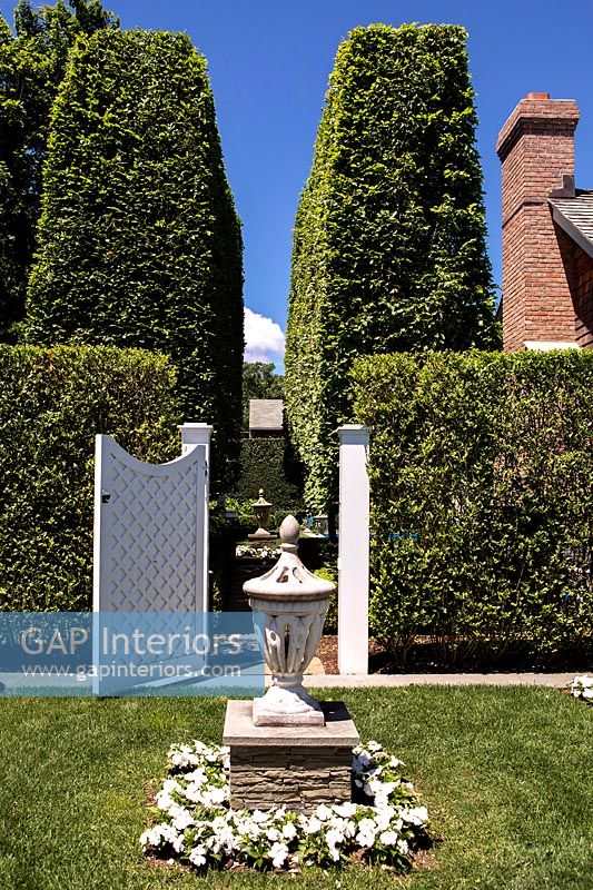 Lanterne en pierre dans un jardin à la française avec porte en bois blanc