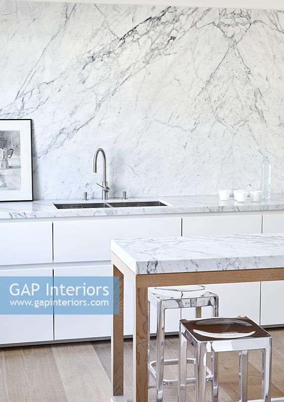 Dos et plans de travail en marbre dans une cuisine moderne blanche