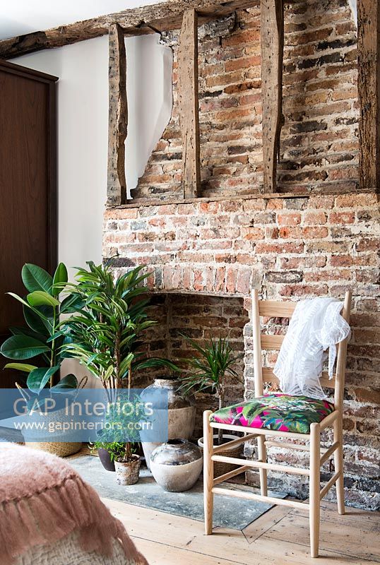 Cheminée en brique avec poutres apparentes et plantes d'intérieur sur foyer