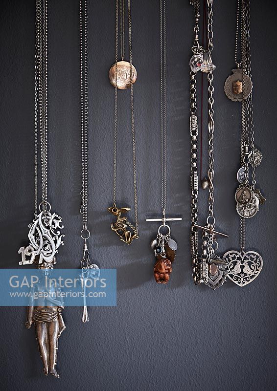 Collection de colliers suspendus sur un mur peint en gris