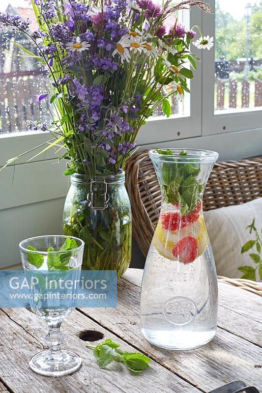 Table de salle à manger de campagne avec des fleurs dans un vase et une cruche d'eau