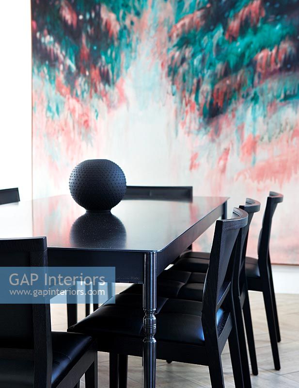 Table et chaises noires avec décor d'œuvres d'art modernes