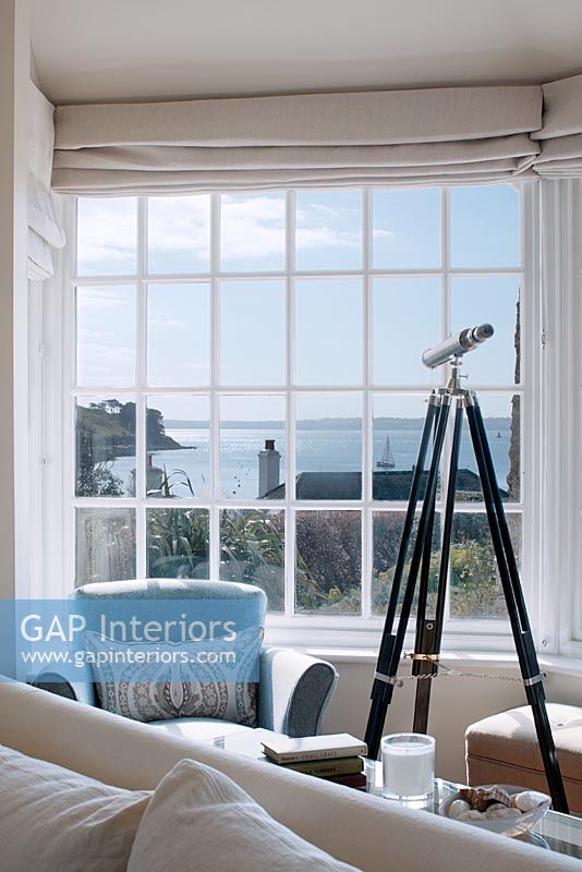 Télescope à côté d'une fenêtre avec vue sur la mer