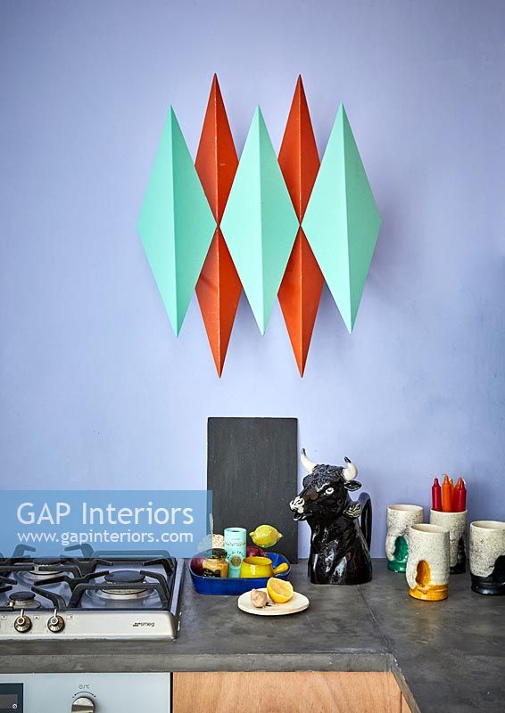 Oeuvre moderne rouge et verte sur le mur de la cuisine sur le plan de travail et la plaque de cuisson au gaz