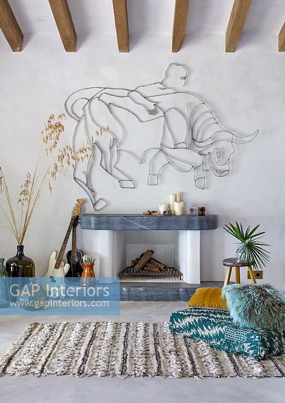 Cheminée avec sculpture de taureau sur le mur, guitares et tapis - salon de campagne moderne