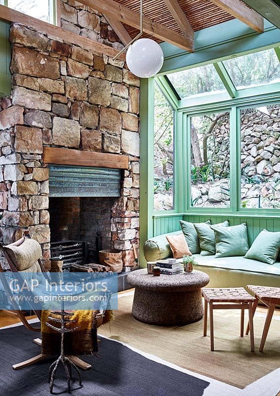 Salon de campagne avec murs en pierre et cadres de fenêtres peints en vert