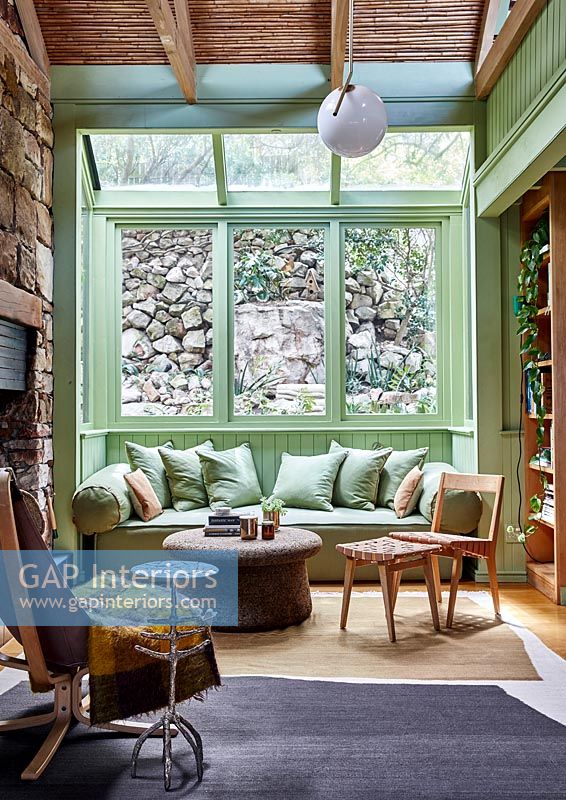 Salon de campagne avec murs en pierre et cadres de fenêtres peints en vert