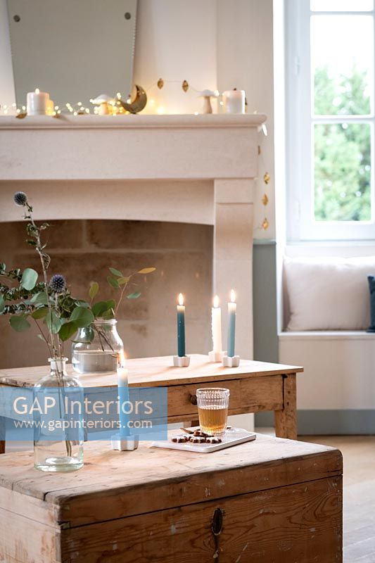 Bougies allumées sur des meubles en bois et guirlandes sur cheminée