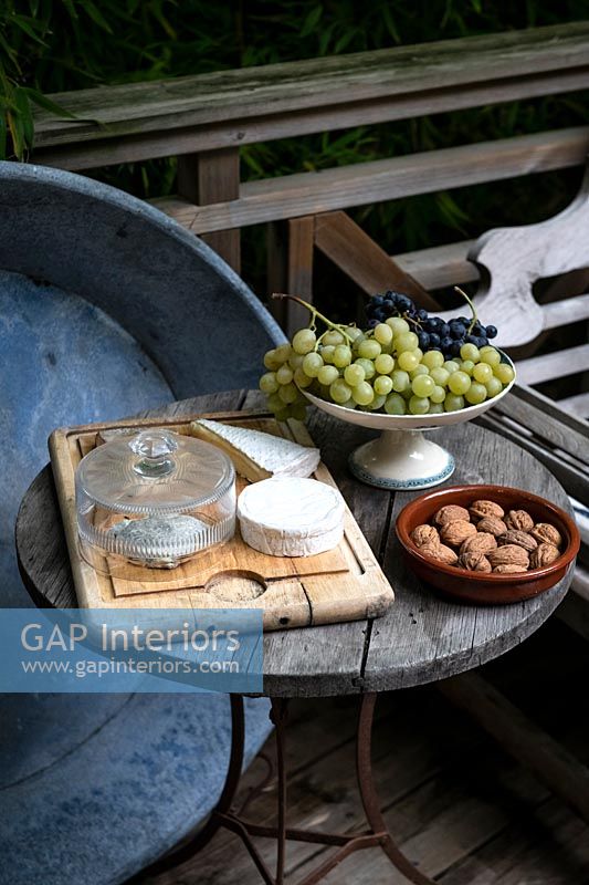 Petite table de jardin avec fromage, fruits et noix