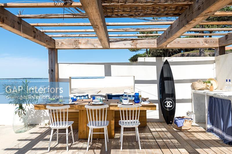 Planche de surf dans une cuisine-salle à manger extérieure donnant sur la mer