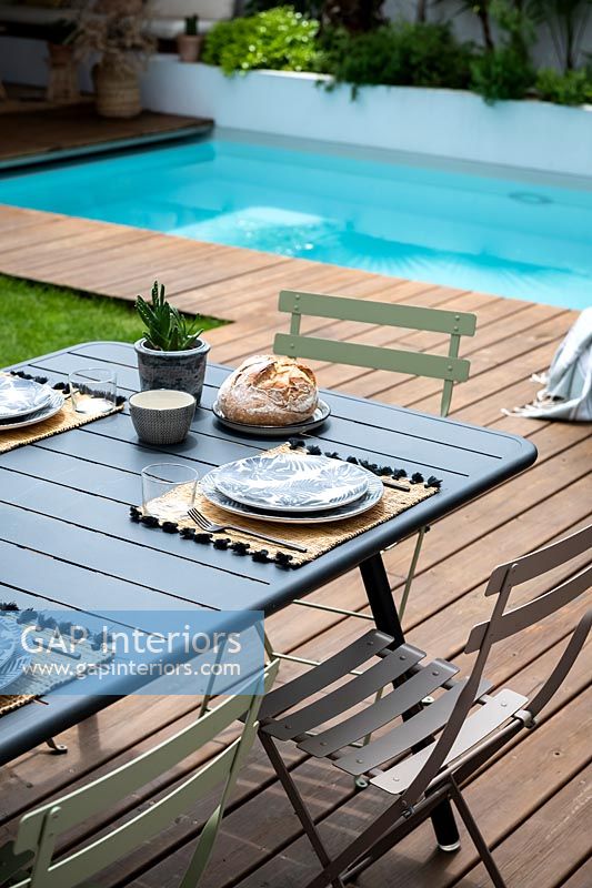 Table à manger en plein air dressée pour le déjeuner à côté de la piscine, l'été