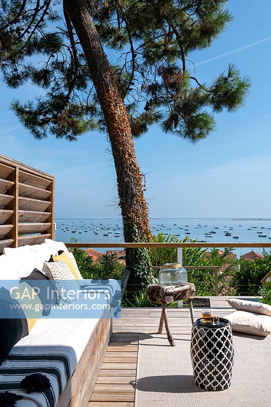 Coin salon sur une terrasse en bois avec vue sur la mer au-delà