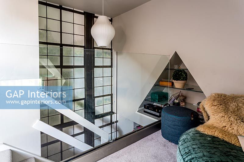 Chambre en mezzanine avec paroi en verre et étagères en alcôve triangulaires