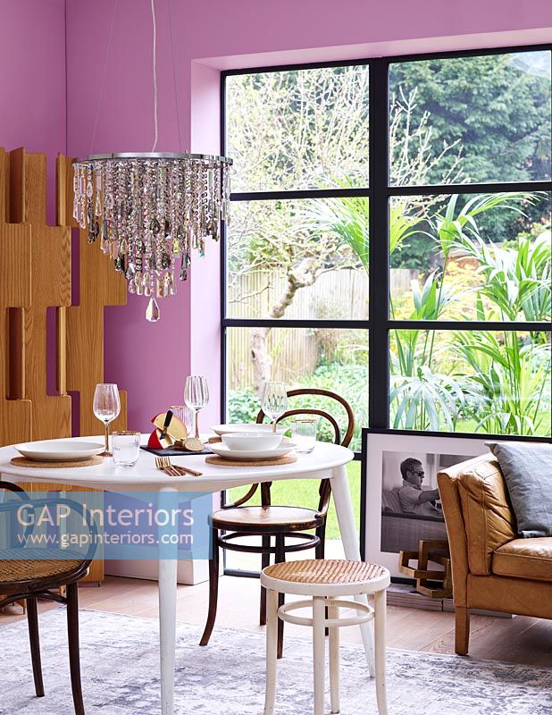 Salle à manger moderne avec murs roses et lustre en cristal