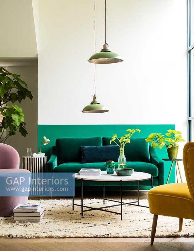 Salon moderne avec mur à moitié peint en vert derrière le canapé