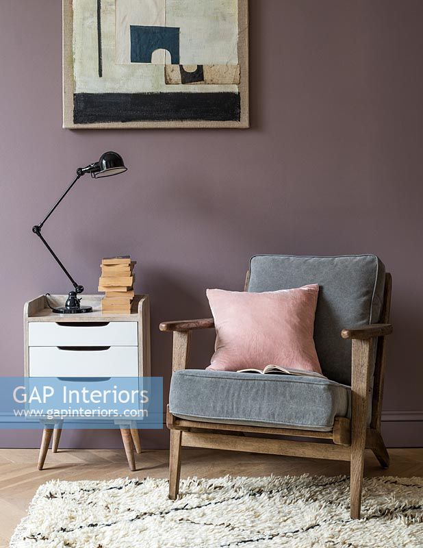 Mur peint en violet derrière le fauteuil et l'armoire