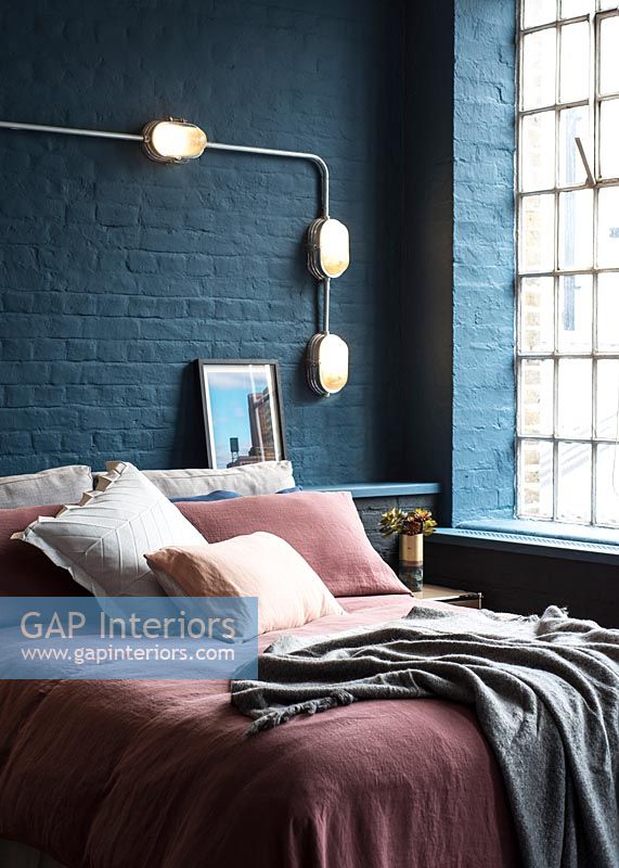 Literie rose et brique peinte bleu foncé dans une chambre moderne