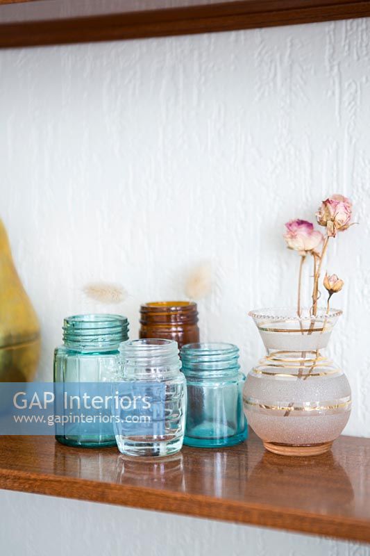 Vase de roses séchées et pots en verre sur une étagère en bois