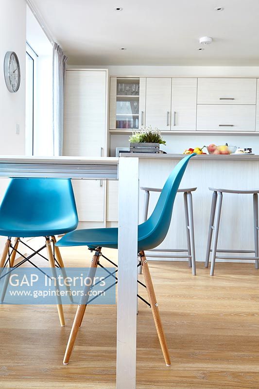 Chaises turquoise dans une cuisine-salle à manger moderne avec parquet
