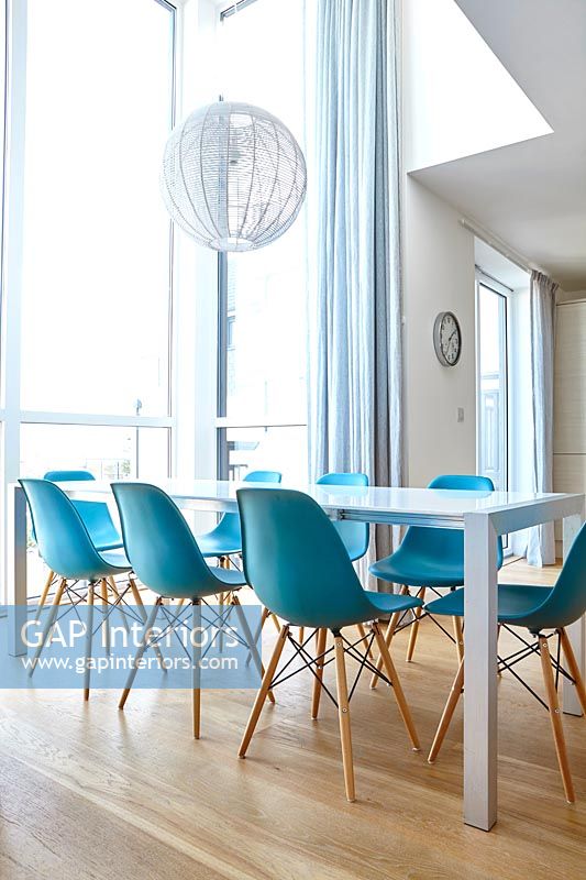 Salle à manger blanche moderne avec chaises turquoise et parquet