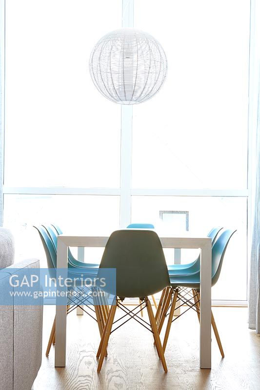 Chaises turquoise autour de la table à manger dans la salle à manger blanche moderne