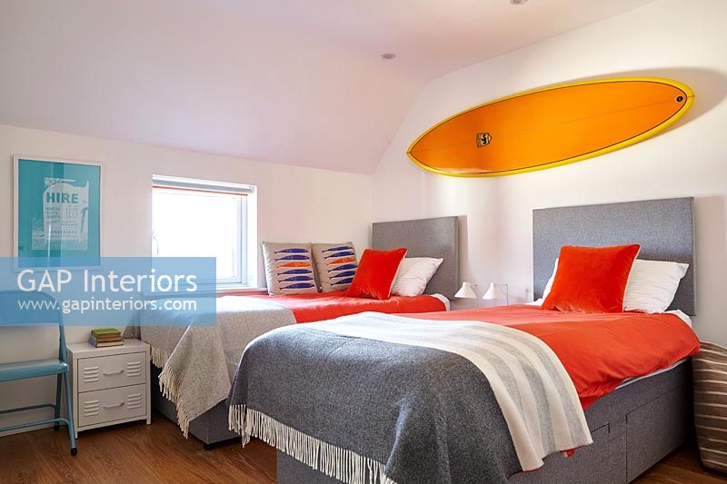 Planche de surf orange vif au-dessus des lits jumeaux