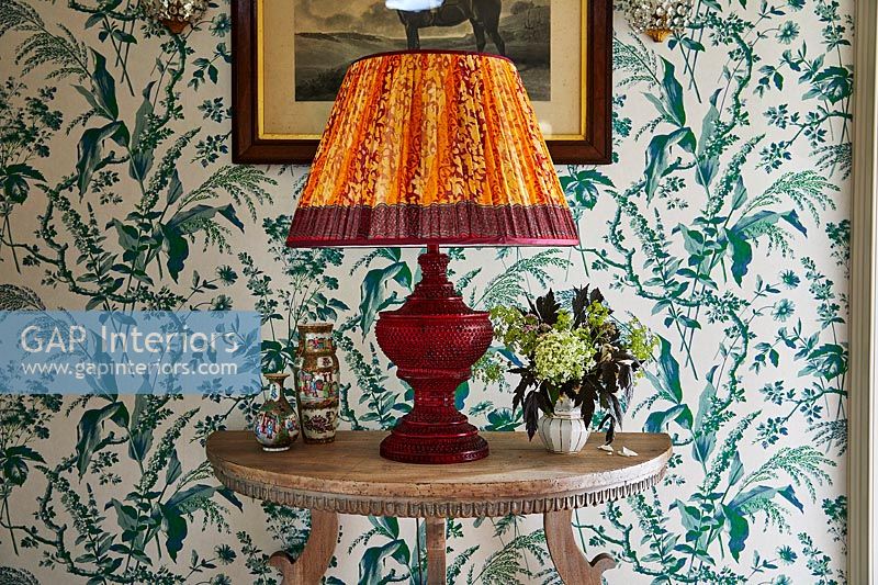Grande lampe orange sur table console en bois dans le couloir