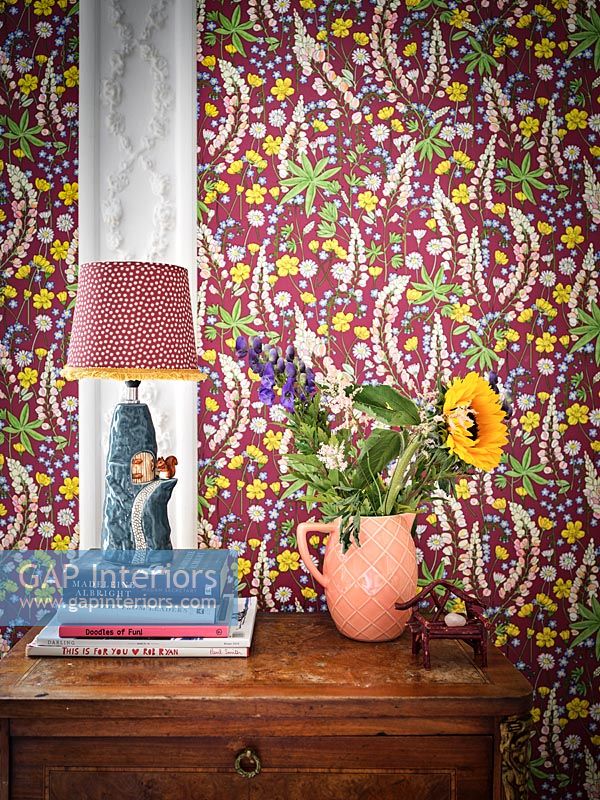 Fleurs et lampe sur table avec papier peint floral coloré sur le mur derrière