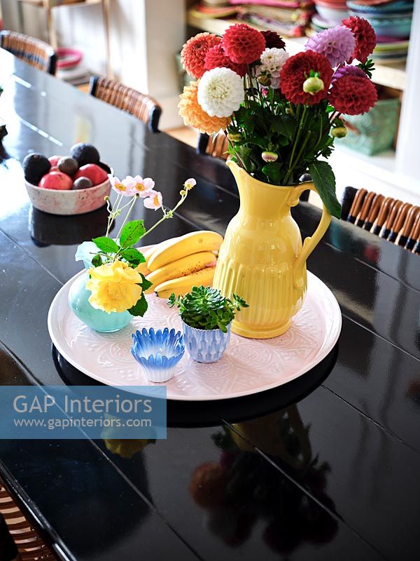 Vase jaune sur plateau rose sur table à manger noire moderne