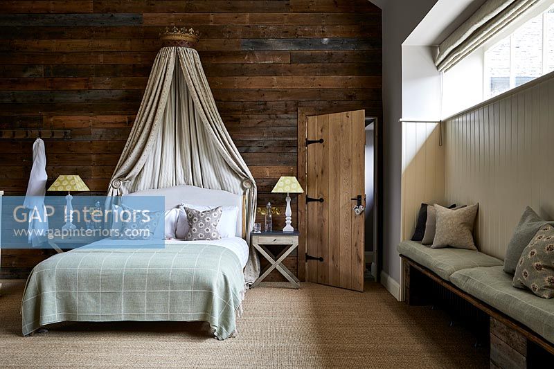 Chambre de campagne avec mur en bois et auvent sur lit