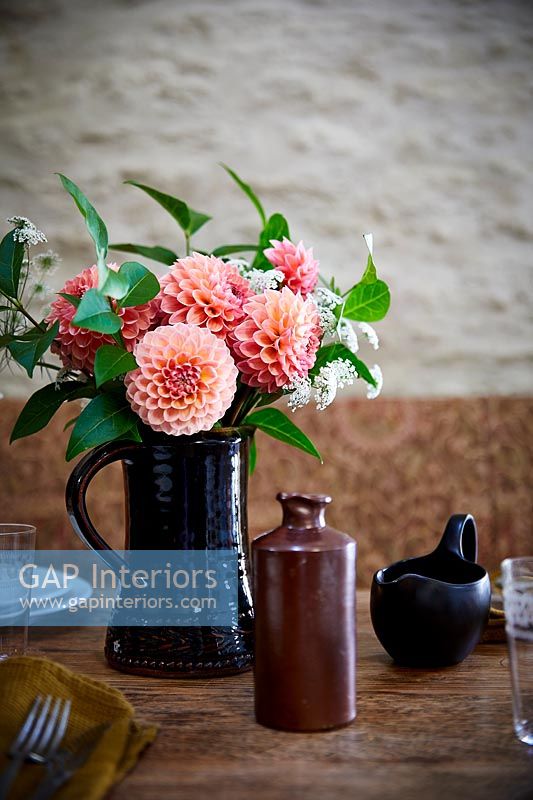 Arrangement de fleurs en pot noir sur la table à manger country