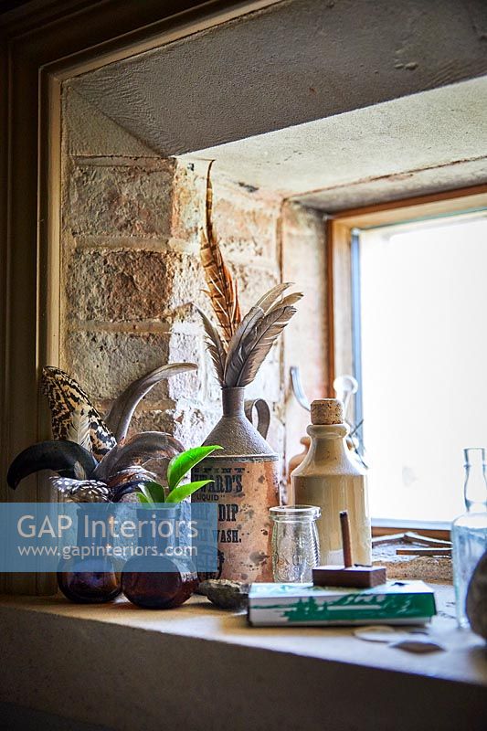 Plumes d'oiseaux dans des vases et des pots sur le rebord de la fenêtre
