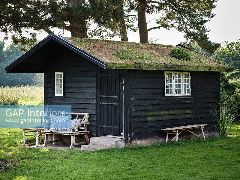 Maison d'été en bois avec toit vivant et banc rustique à l'extérieur
