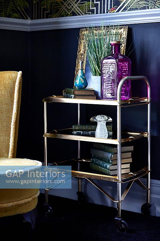 Chariot vintage en or comme table d'appoint dans un salon éclectique