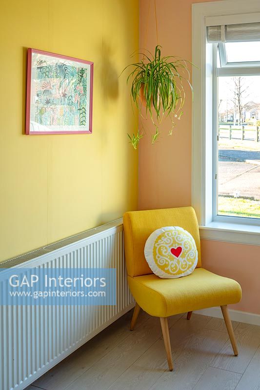 Fauteuil jaune dans un salon moderne avec des murs peints de couleurs vives.