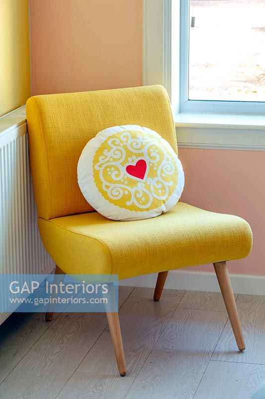 Coussin à motifs de cœur sur une chaise jaune moderne