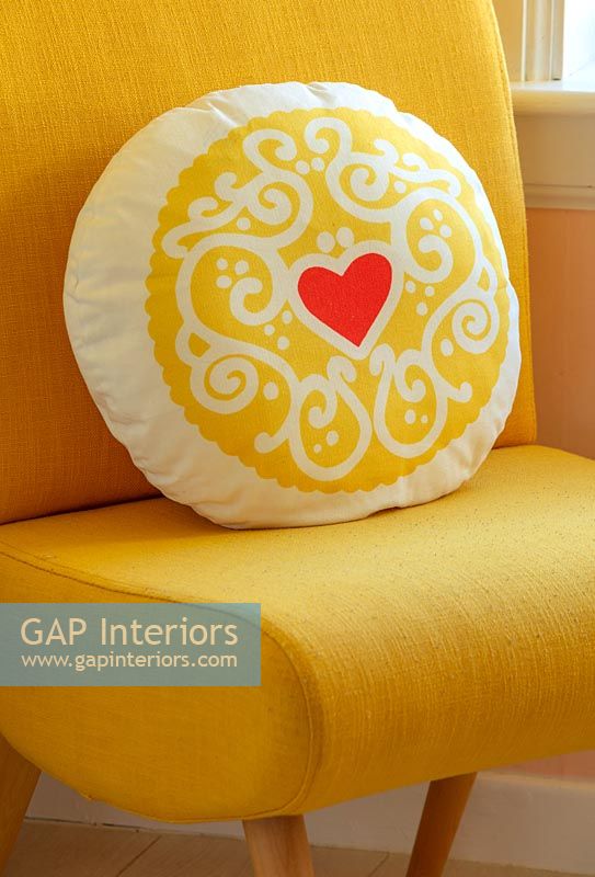 Coussin jaune avec motif coeur rouge sur chaise jaune