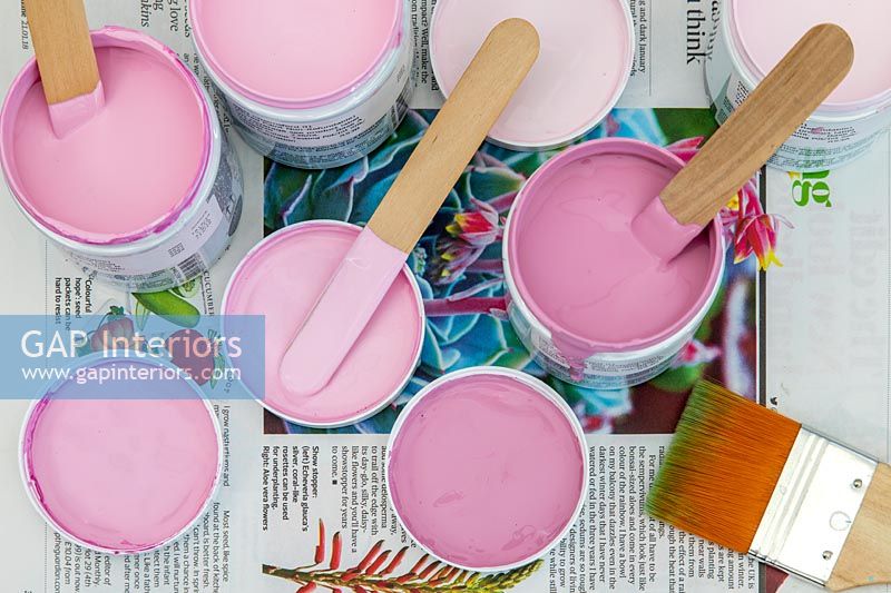 Pots de peinture avec différentes nuances de rose poussiéreux, pinceaux et rouleaux