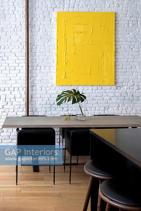 Salle à manger moderne avec mur de briques peintes en blanc et illustrations jaunes