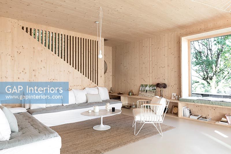Salon moderne en bois avec baie vitrée et escalier
