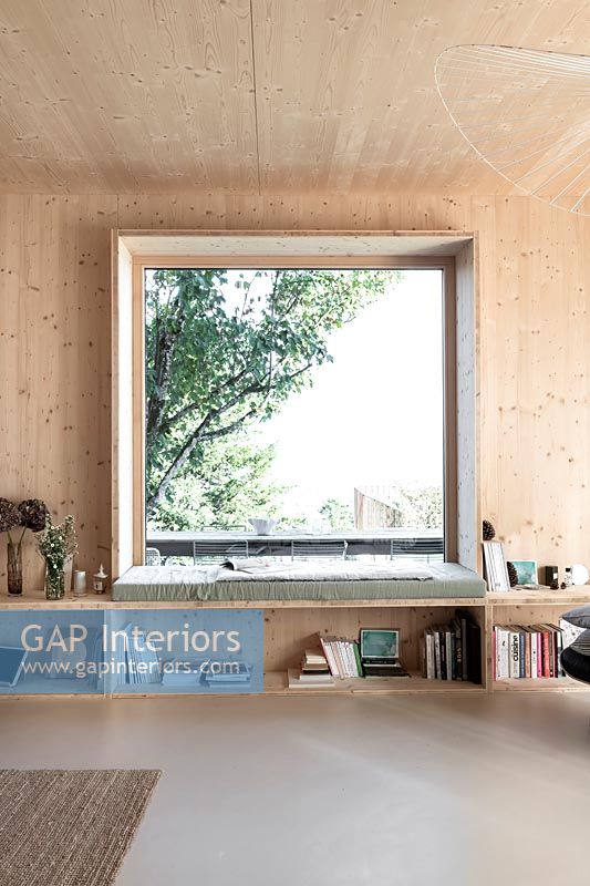 Grande baie vitrée carrée dans un salon moderne revêtu de bois