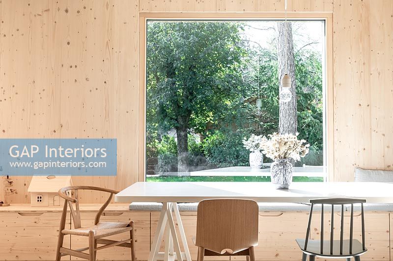 Salle à manger en bois moderne avec grande baie vitrée donnant sur jardin