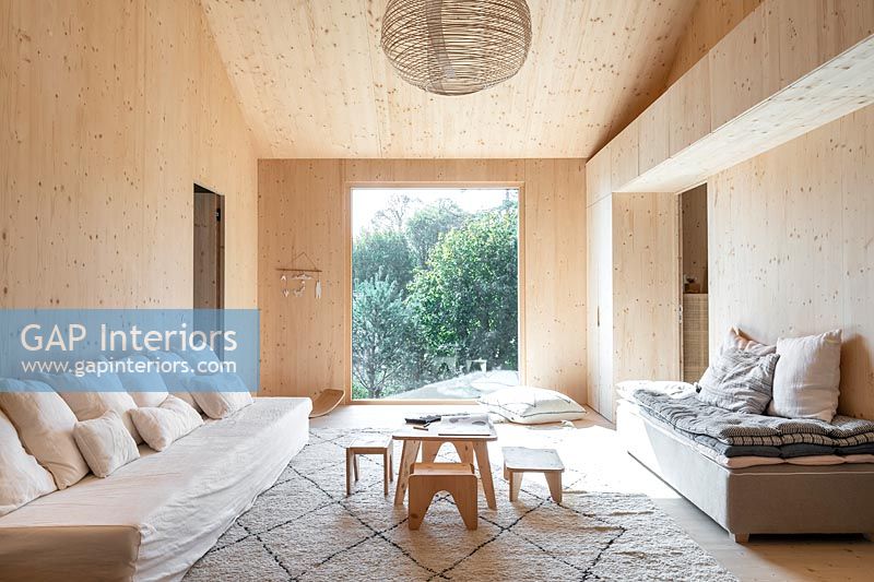 Salon moderne en bois avec grande baie vitrée donnant sur le jardin