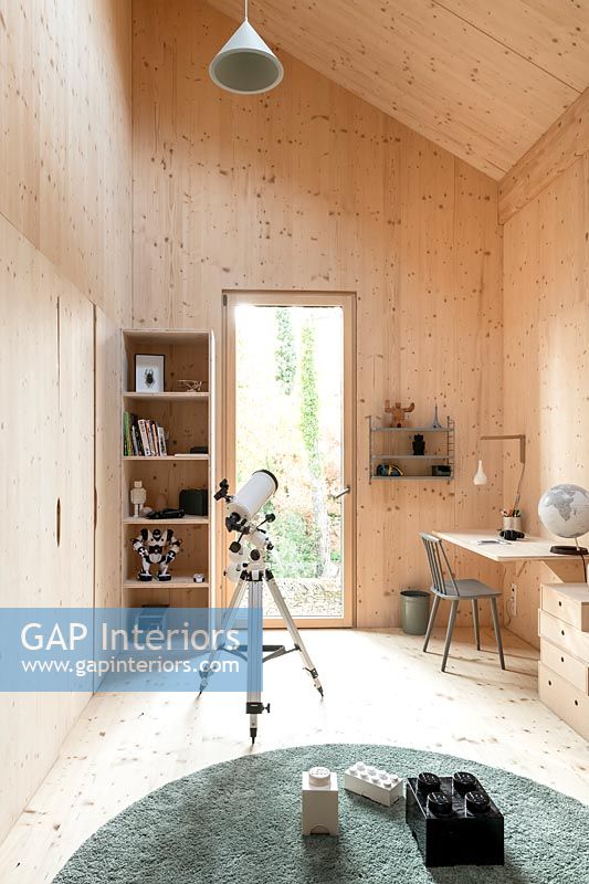 Chambre d'enfants moderne revêtue de bois avec télescope et bureau