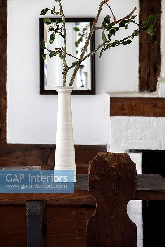 Vase long blanc avec des branches d'arbres comme arrangement dans la salle à manger du pays