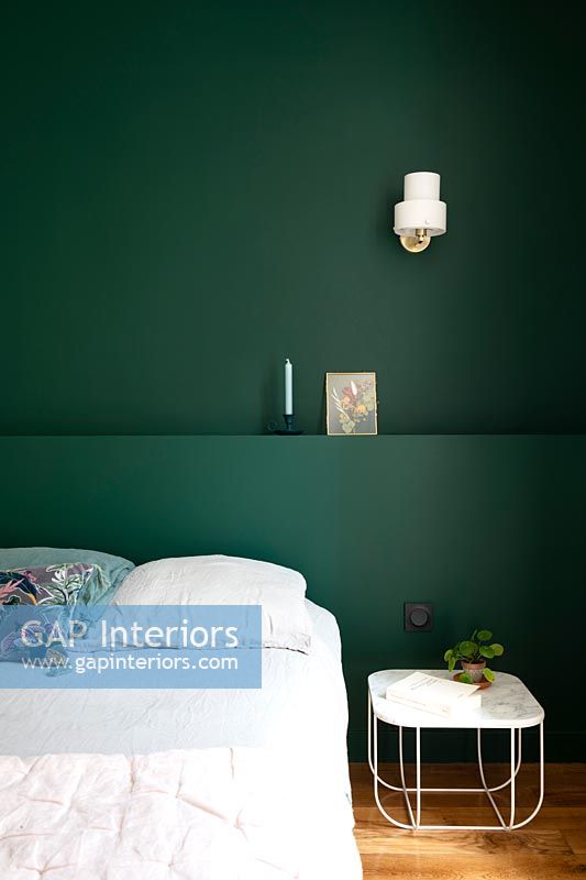 Mur et tête de lit peints en vert foncé dans la chambre moderne