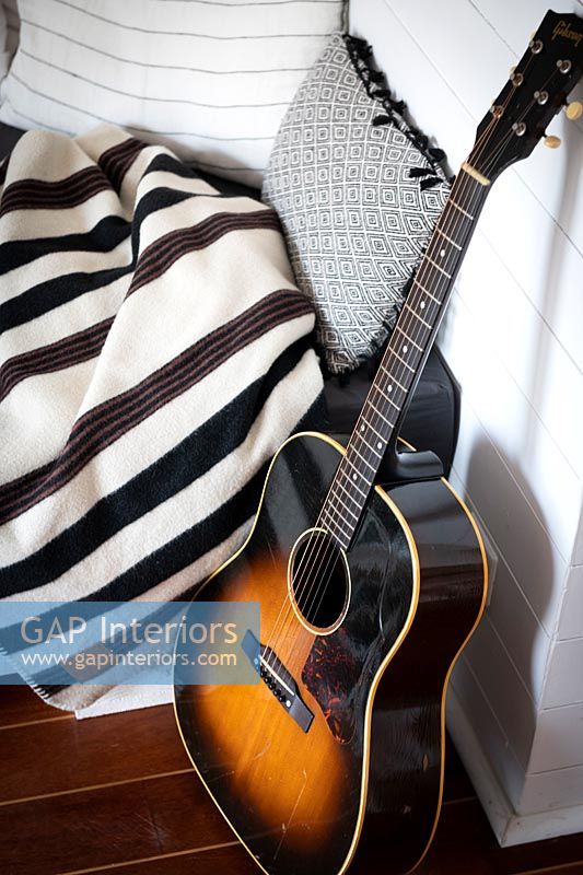 Gros plan de la guitare à côté de couvertures et coussins
