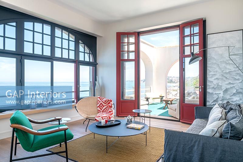 Salon moderne avec vue sur la mer et portes-fenêtres ouvertes sur la terrasse